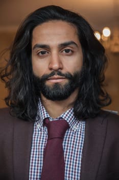 Front view portrait of a young businessman looking at the camera with a serious expression on his face.