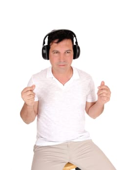 A good looking man sitting on a chair with his headphones on and.listening to music with is eyes closed, isolated for white background.