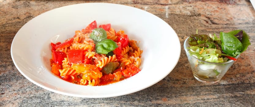 spiral pasta,fusilli,cooked with tomato sauce on a plate,Parmesan cheese and salad