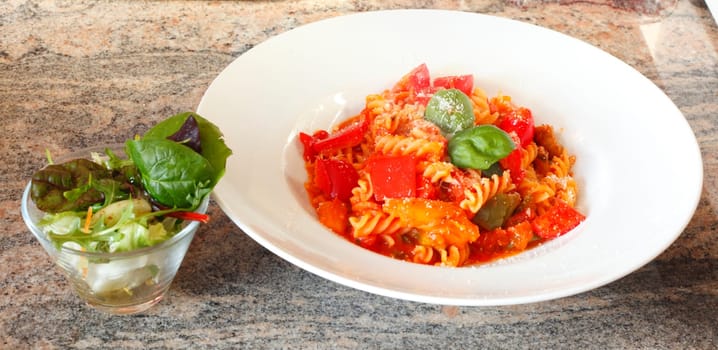 spiral pasta,fusilli,cooked with tomato sauce on a plate,Parmesan cheese and salad
