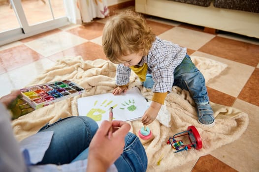 A mother and child spend quality time creating hand-painted artwork together on a cozy indoor afternoon filled with creative expression and parental joy.
