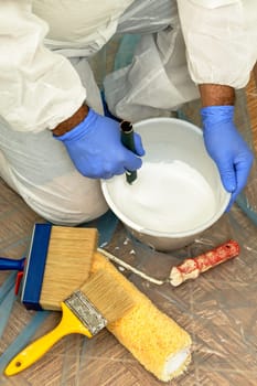 Painter paints the wall with the tint of white. Wall with serious moisture problems. Detail of the brush. white dye is prepared for the painter's job.