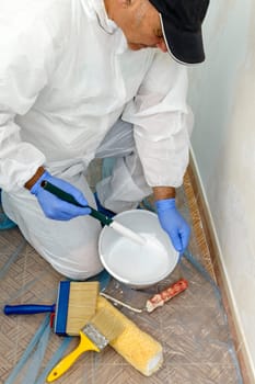Painter paints the wall with the tint of white. Wall with serious moisture problems. Detail of the brush. white dye is prepared for the painter's job.