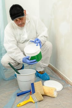 Painter paints the wall with the tint of white. Wall with serious moisture problems. Detail of the brush. white dye is prepared for the painter's job.