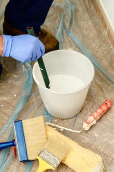 Painter paints the wall with the tint of white. Wall with serious moisture problems. Detail of the brush. white dye is prepared for the painter's job.