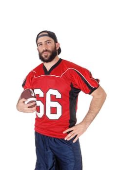 A football player in his red jersey and his brown football in his hand,.looking into the camera, isolated for white background.