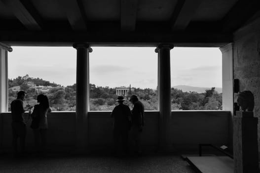 ATHENS, GREECE - SEPTEMBER 2, 2014: People looking at view ancient agora and temple of hephaestus from stoa of attalos. Black and white.