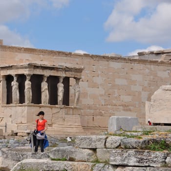 ATHENS, GREECE - MAY 6, 2014: Woman in front of the Porch of Caryatids. Erechtheion ancient temple ruins at the Acropolis of Athens, Greece.
