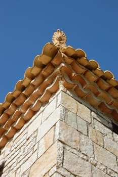 Ceramic antefix decorative pottery ornament on the roof of a house in Greece. Architectural detail.