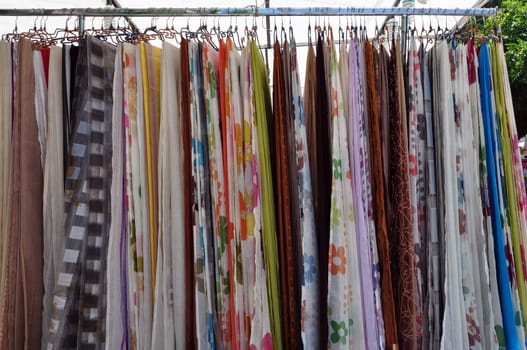 Colorful drapes for sale at street market. Abstract textile fabric background.