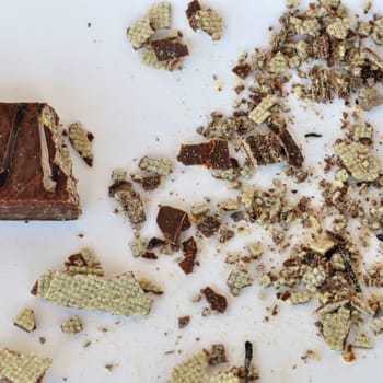 Chocolate wafer sweet dessert and crumbs on white background.