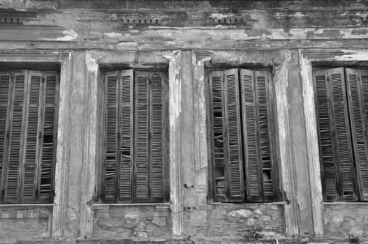 Broken wooden window shutters and textured wall of an abandoned house. Urban decay black and white.