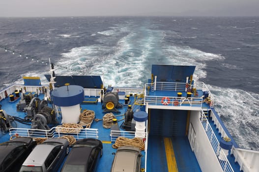 Ferry boat at sea. Cars and equipment on ship deck.