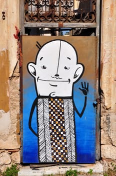 ATHENS, GREECE - APRIL 15, 2014: Funny cartoon character abstract graffiti on the boarded up door of an abandoned house.