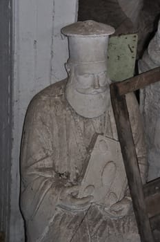 ATHENS, GREECE - JANUARY 15, 2013: Dusty statue orthodox priest with holy bible in the abandoned studio of artist Nikolaos Pavlopoulos (1909 - 1990).
