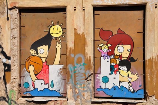 ATHENS, GREECE - APRIL 15, 2014: Colorful graffiti artwork happy cartoon figures on boarded up windows. Youth culture urban street art.