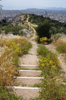 View of Athens Greece from Philoppapos hill of the muses. Crooked ancient trail distant city sea and sky horizon.