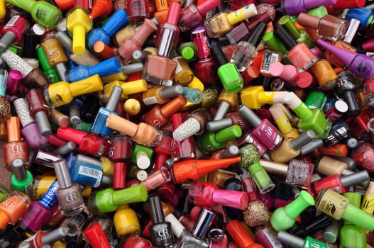 ATHENS, GREECE - AUGUST 15, 2014: Nail polish paint bottles pile of cosmetic products abstract background.