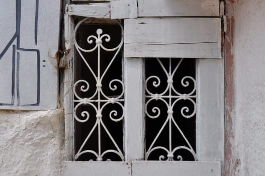 Old window with decorative metal motif. Abandoned boarded up house.