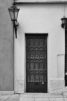 Old door with metal pattern and old fashioned street light. Black and white.