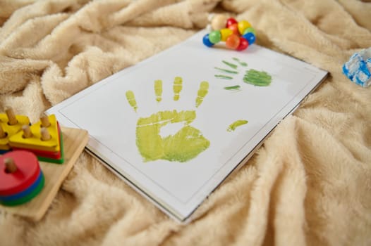Colorful child handprint artwork adorning a sheet on a cozy blanket surrounded by toys representing creativity, play, and joyful moments.