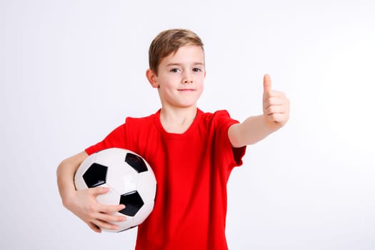 boy in red shirt with soccer ball and thumb up in front of white background