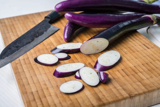 japanese eggplant on wooden board with cooking knife and pak choi salad