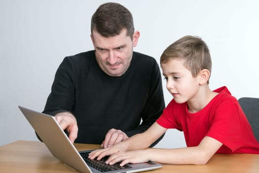 father and son using computer togetherat home