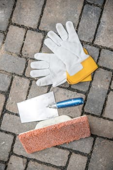 trowel, sponge board and work gloves on stone ground