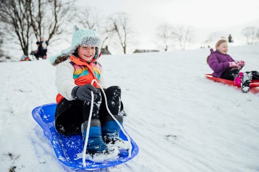 Close up shot of a little girl on a snow sled in a community race.