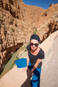 Female tourist relaxing on winding road bank in Dades Valley, Atlas mountains, Morocco.