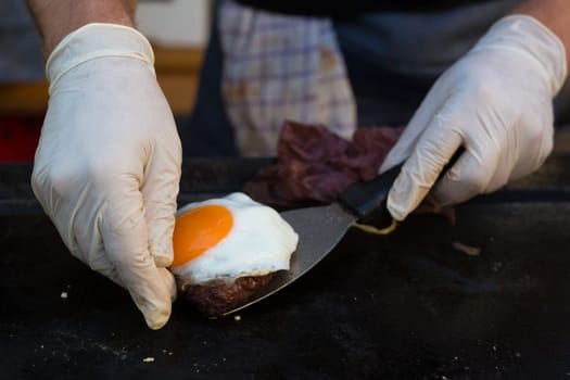 Chef making beef burgers outdoor on open kitchen international food festival event. Street food ready to serve on a food stall.