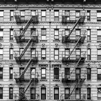 A fire escape of an apartment building in New York city. Graphical black and white image.