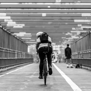 Man riding his bike in the cycling lane on Williamsburg Bridge, Brooklyn, New York City, USA. Black and white image.