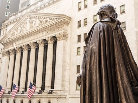 View from Federal Hall of the statue of George Washington and the Stock Exchange building in Wall Street, New York City, USA.