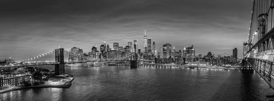 Brooklyn, Brooklyn park, Brooklyn Bridge, Janes Carousel and Lower Manhattan skyline at night seen from Manhattan bridge, New York city, USA. Black and white wide angle panoramic image.