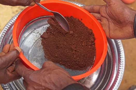 Sifting grinded coffee powder in tray