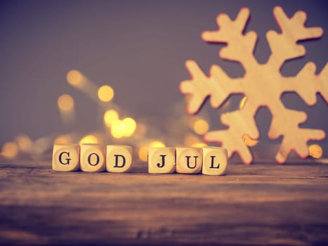 God Jul, Scandinavian Merry Christmas on wooden dices with blurred lights and decoration
