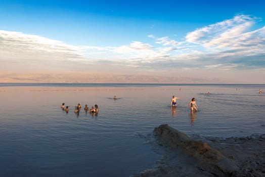 Dead Sea, Israel, May 05, 2017 : Photo of people  floating on surface Dead Sea enjoy summer sun and vacation. Recreation tourism, healthy lifestyle, free time concept