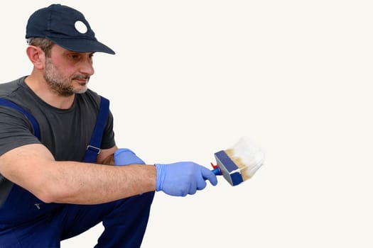 Painter paints the wall with the tint of white. Wall with serious moisture problems. Detail of the brush. white dye is prepared for the painter's job.