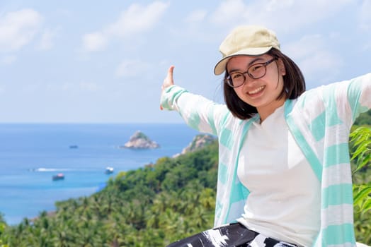 Women tourists extend the arms happily at high viewpoint to see the beautiful nature landscape of the sea and island on top of the Koh Tao island is a famous attractions in Surat Thani, Thailand