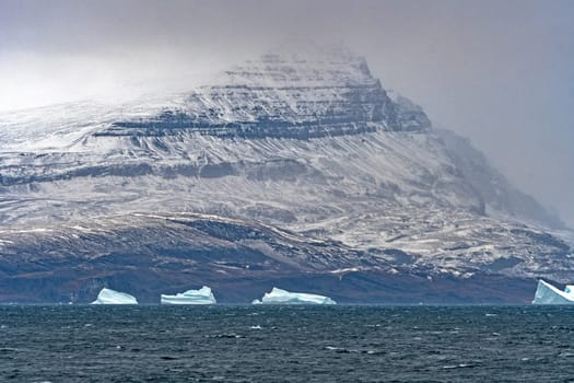 Coastal Mountain Looming Through the Clouds on a Remote Coast of Greenland