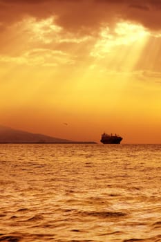 seascape image of cargo ship over sunset