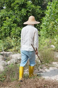 Asian farmer cleaning land under hot sun.