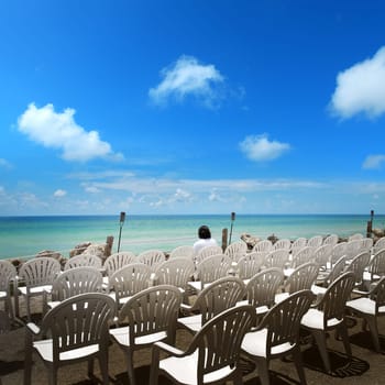man sitting on chair at beach over clear sky