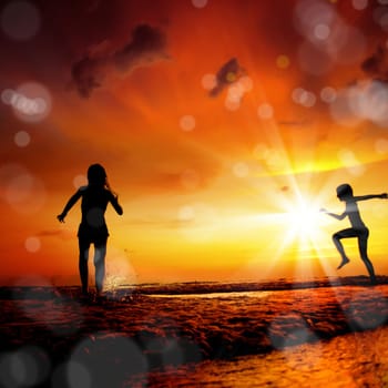 children running in to water over sunset at beach