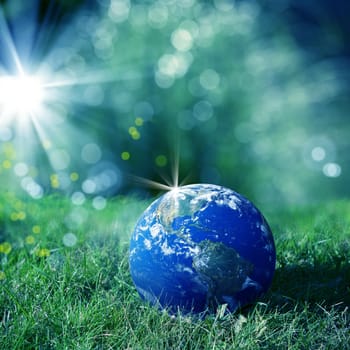 conceptual image of globe on green landscape and light. Furnished NASA image used for this image.