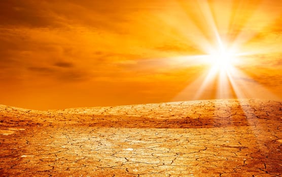 conceptual image of dried and cracked landscape over sunset.