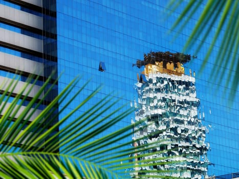 close up architectural detail from tall glass building and palm tree in Thailand