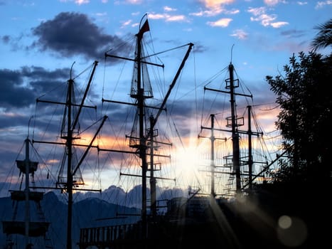 sailing boats silhouetted by sunset light in harbor of Antalya